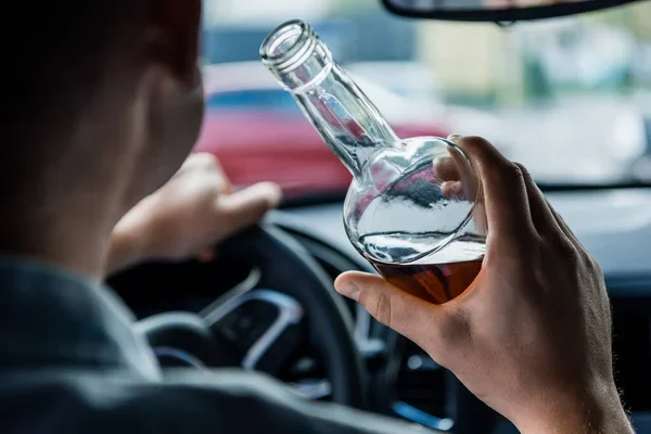 Driver drinking from a bottle of liquor