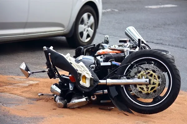 Motorcycle lying on its side beside a car