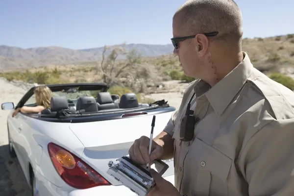 Highway patrol officer speaking with a driver