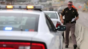 Highway patrol officer walking beside a stopped car