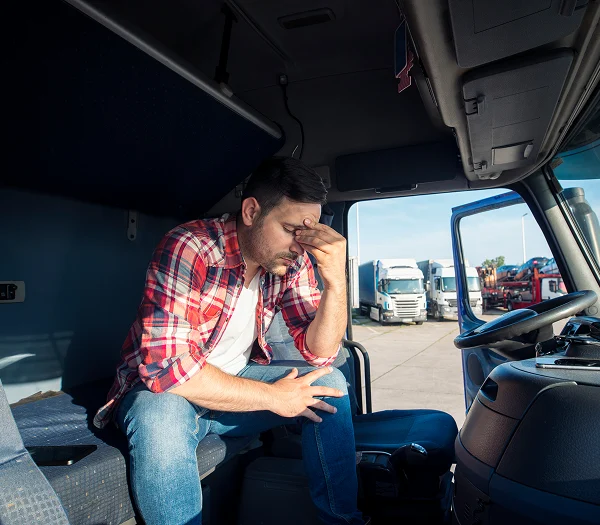 Truck driver holding his head while seated in the cab